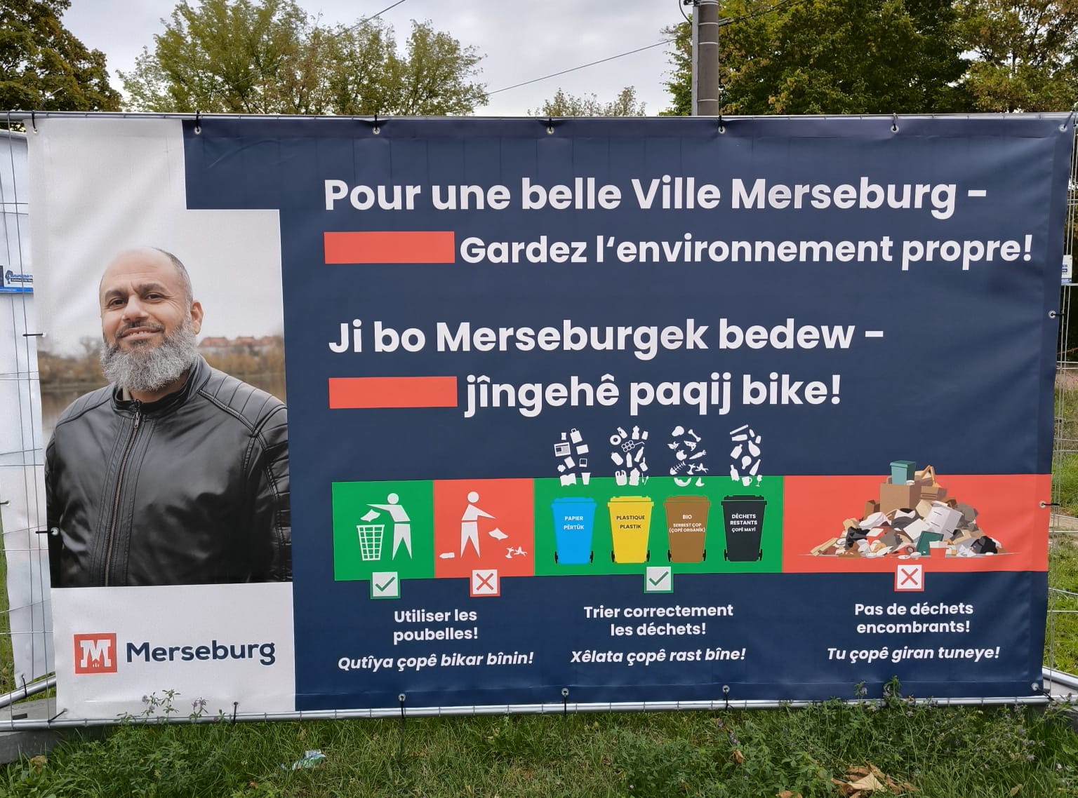 Banner mit Mülltrennungshinweisen in Merseburg-Süd auf Arabisch und Persisch, mit Porträt eines lokalen Unterstützers – sauberes Merseburg Mülltrennung