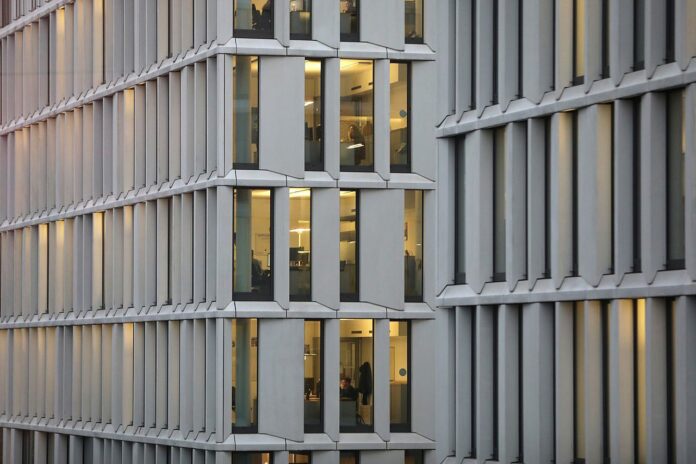 Symbolbild Nachtarbeit und Schichtarbeit Beleuchtete Bürofenster einer Fassade am Abend, Symbolbild zu Schicht- und Nachtarbeit