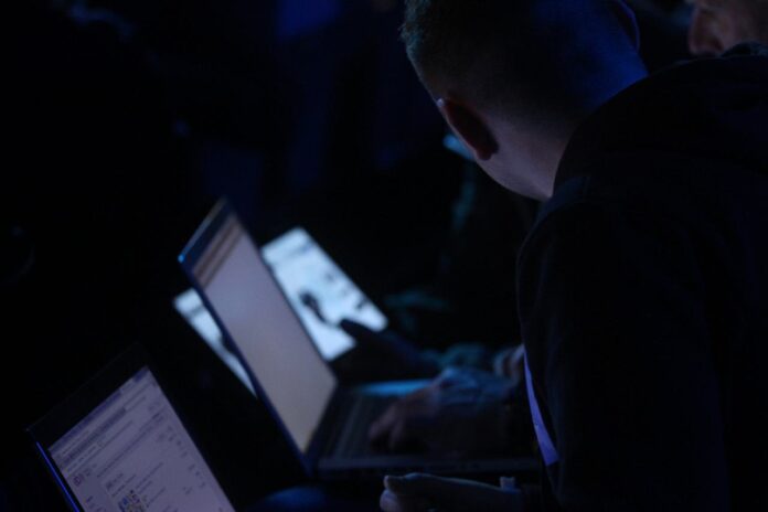 Symbolbild IT-Sicherheit Person arbeitet nachts an mehreren Laptops, Symbolbild IT-Sicherheit